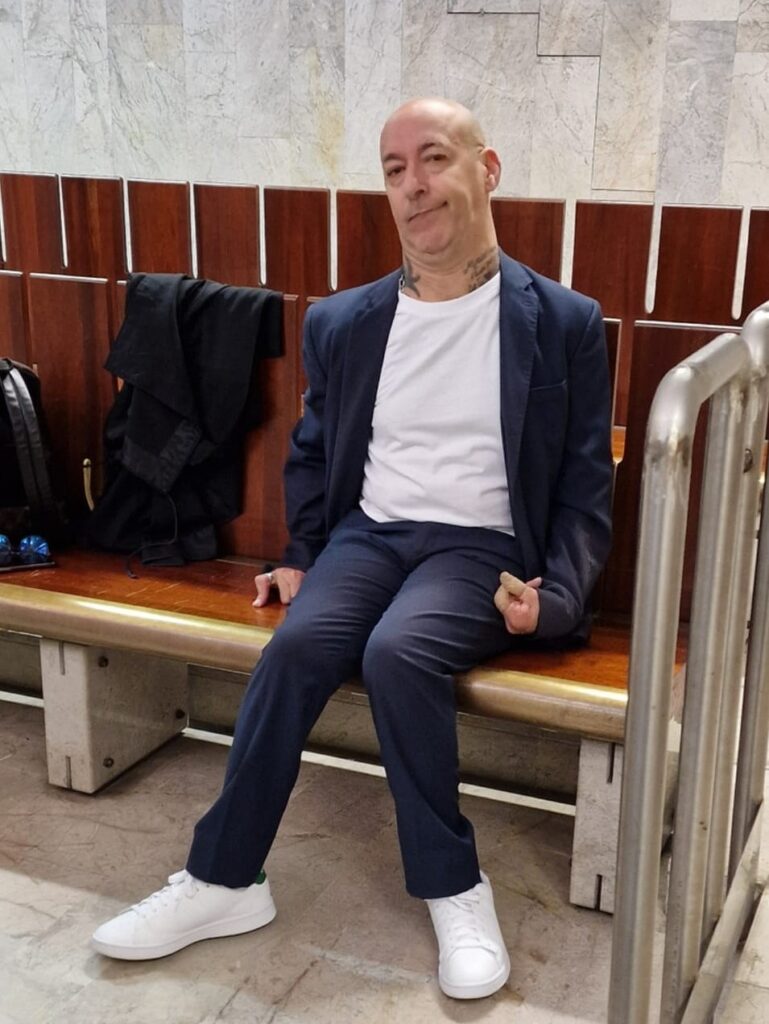 pier seduto in tribunale con tshirt bianca e scarpe da ginnastica bianche